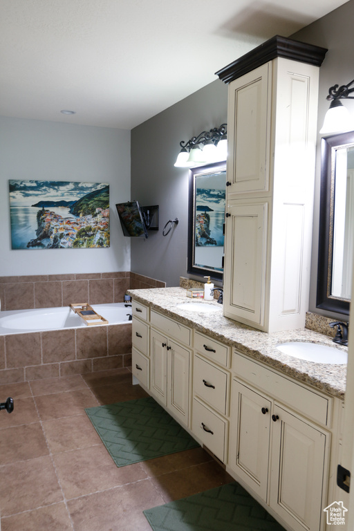 Bathroom with tile patterned floors, a relaxing tiled tub, and vanity