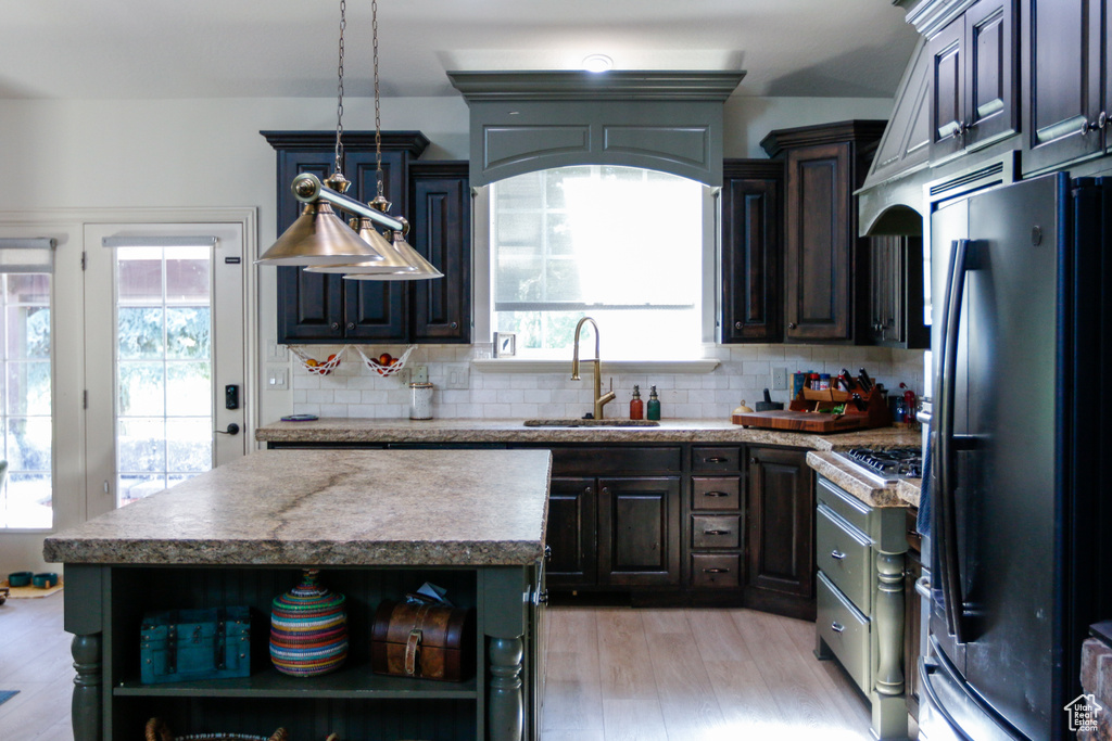 Kitchen featuring sink, light hardwood / wood-style flooring, backsplash, appliances with stainless steel finishes, and a center island