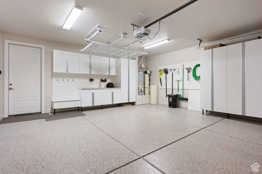 Garage featuring a garage door opener and water heater