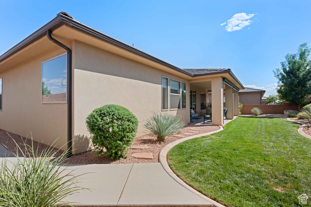 Back of house with a lawn and a patio