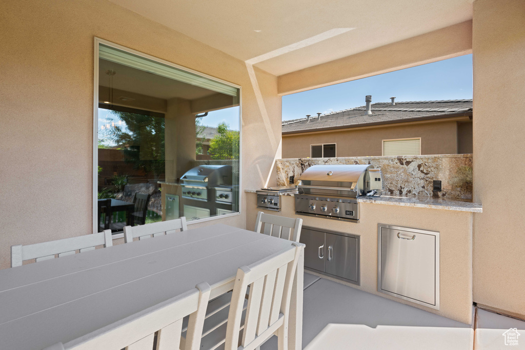 View of patio with exterior kitchen and a grill