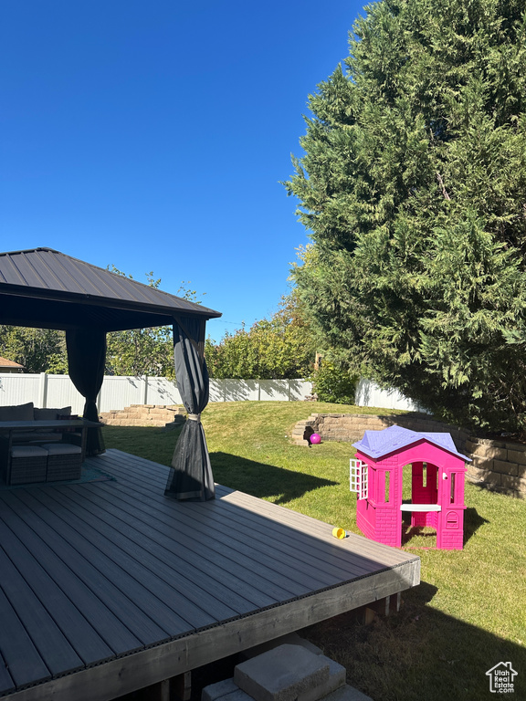 Wooden deck featuring a gazebo and a yard