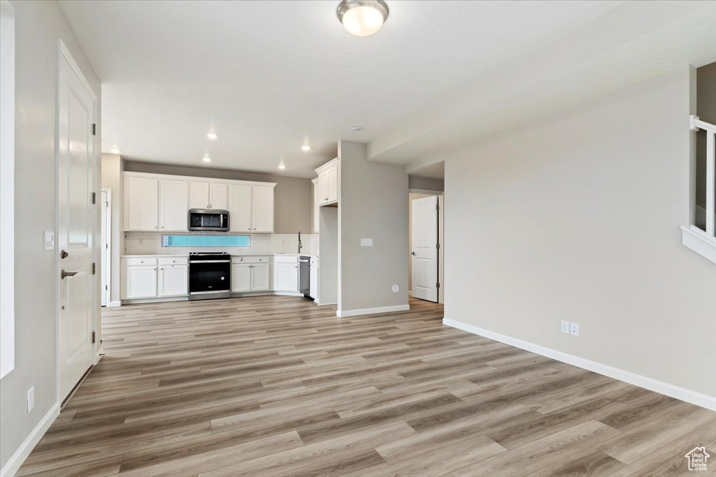 Kitchen featuring light hardwood / wood-style floors, white cabinetry, and stainless steel appliances