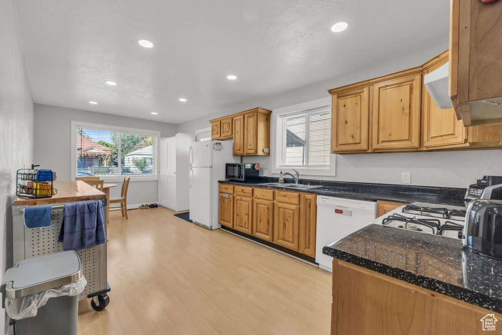 Kitchen with light hardwood / wood-style flooring, kitchen peninsula, sink, and white appliances