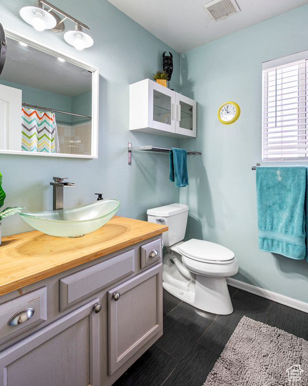 Bathroom with vanity, toilet, and curtained shower