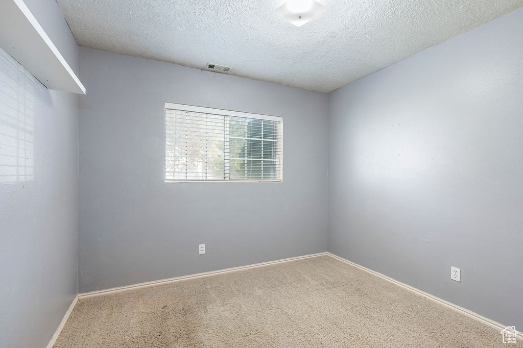 Carpeted empty room with a textured ceiling