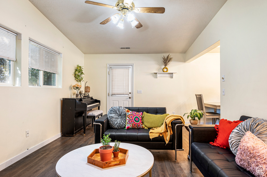 Living room featuring lofted ceiling, ceiling fan, and dark hardwood / wood-style flooring