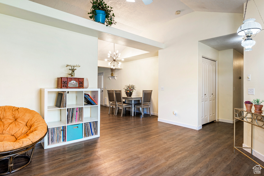 Living area with lofted ceiling, an inviting chandelier, dark hardwood / wood-style floors, and a textured ceiling