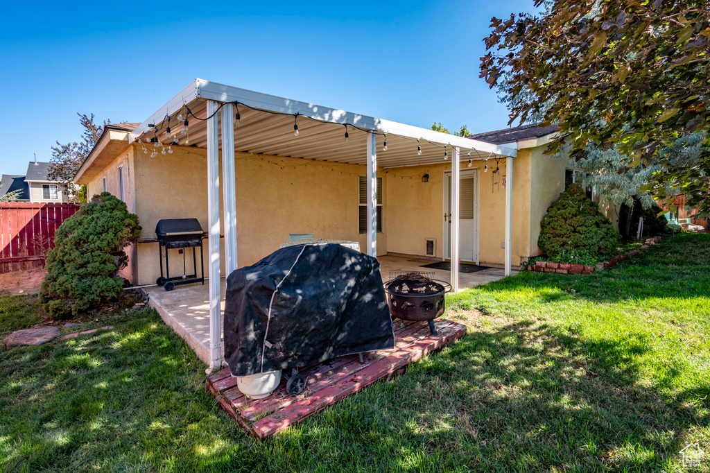 Rear view of property featuring a fire pit, a patio, and a lawn