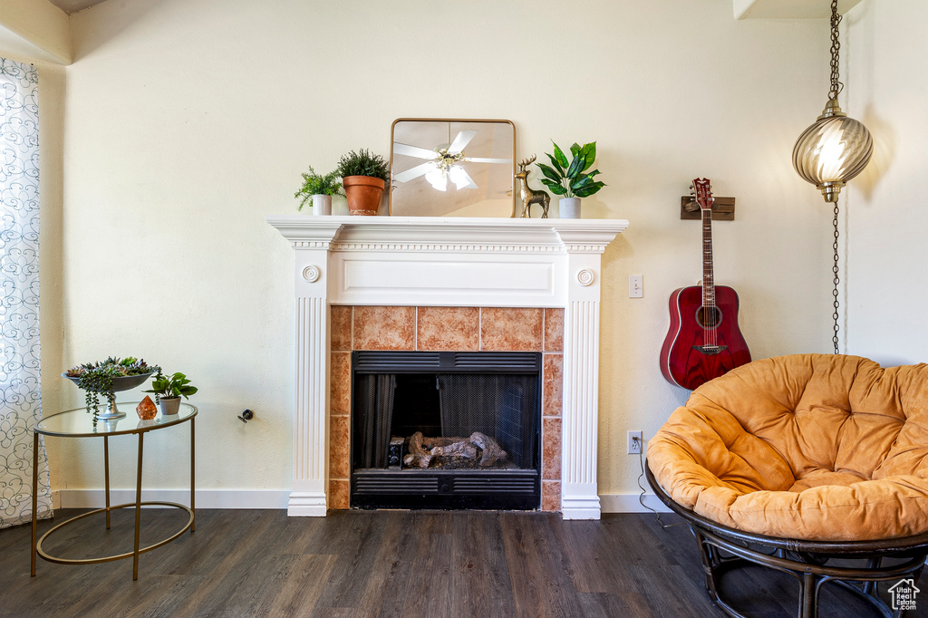 Living area featuring dark wood-type flooring, ceiling fan, and a tile fireplace