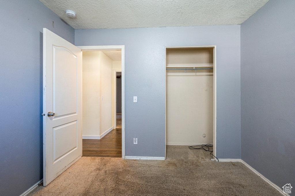 Unfurnished bedroom with a textured ceiling, a closet, and carpet flooring