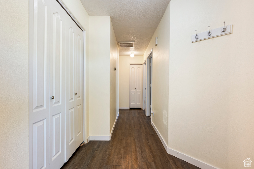 Hallway featuring a textured ceiling and dark wood-type flooring