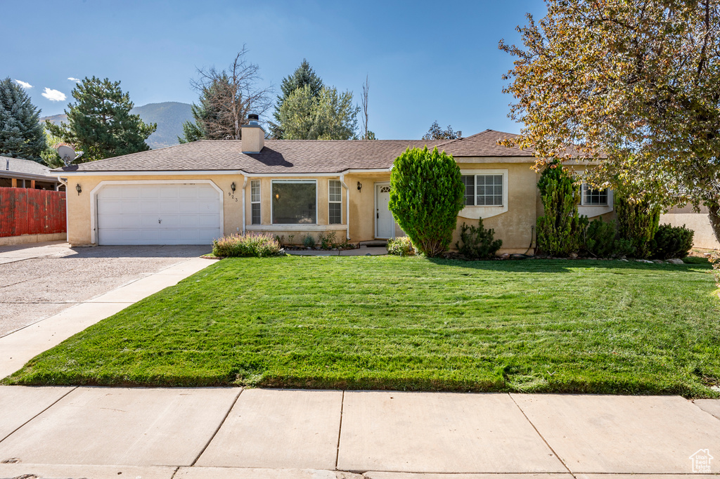 Ranch-style home featuring a garage and a front lawn