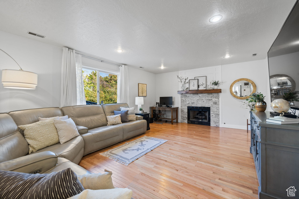 Living room featuring a textured ceiling, a fireplace, and light hardwood / wood-style floors