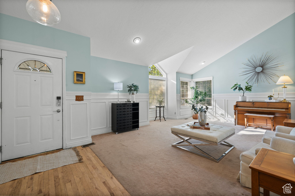 Living room with vaulted ceiling and light hardwood / wood-style floors