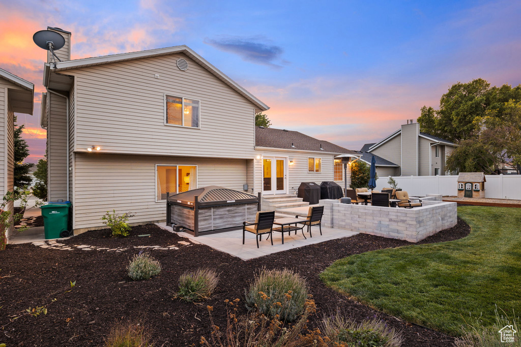 Back house at dusk with outdoor lounge area, a patio, and a yard