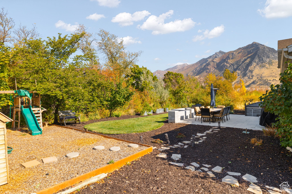 View of yard with a playground, a mountain view, and a patio area