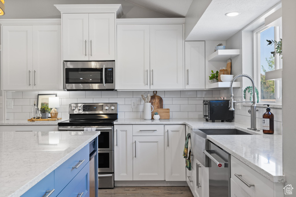 Kitchen with light stone countertops, white cabinetry, and stainless steel appliances