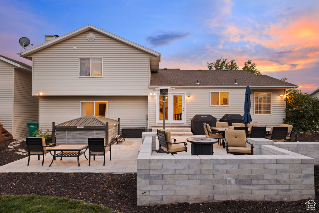 Back house at dusk featuring a patio and an outdoor living space with a fire pit