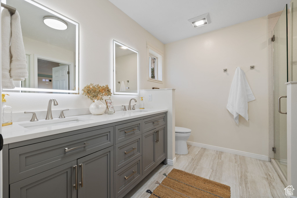 Bathroom with an enclosed shower, wood-type flooring, vanity, and toilet