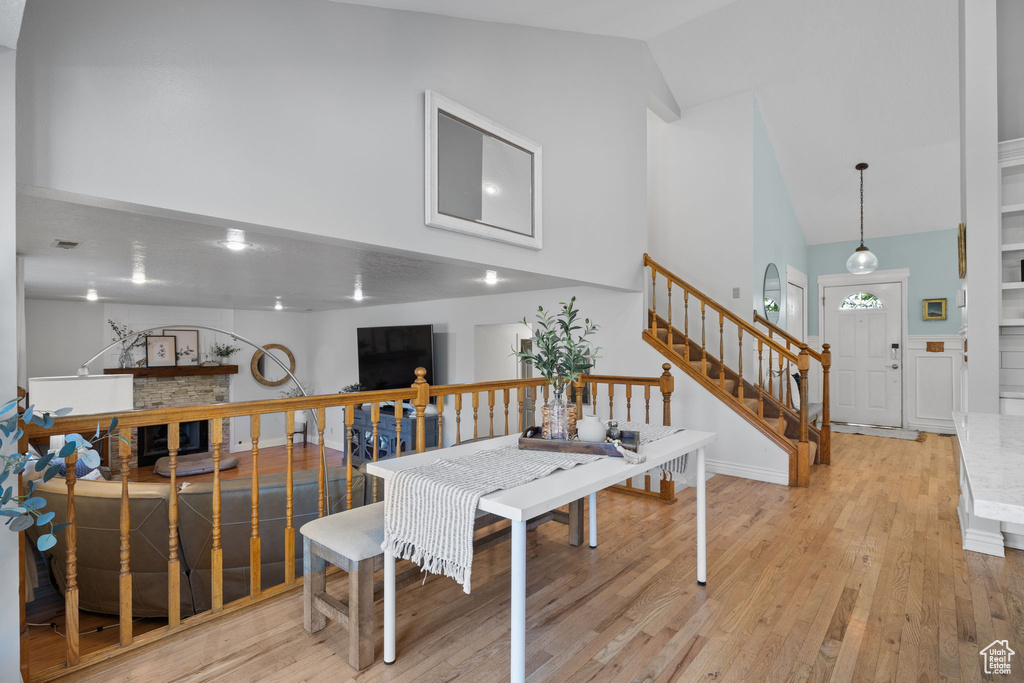 Dining area with lofted ceiling, a fireplace, and light hardwood / wood-style floors