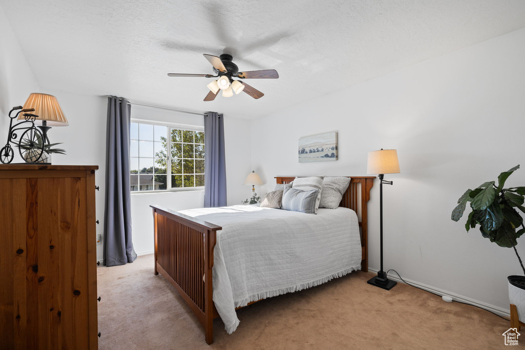 Bedroom featuring light colored carpet, a textured ceiling, and ceiling fan