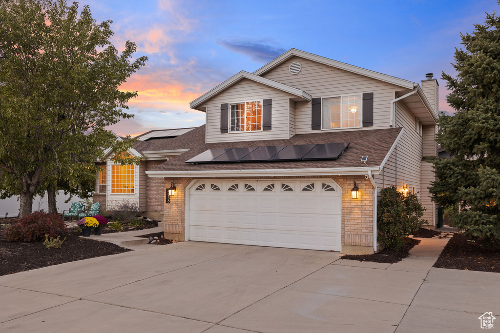 View of front of property with solar panels and a garage