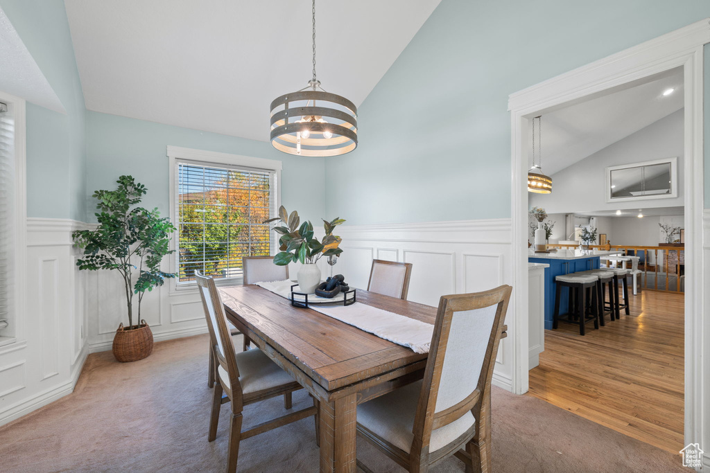 Carpeted dining area featuring lofted ceiling and an inviting chandelier