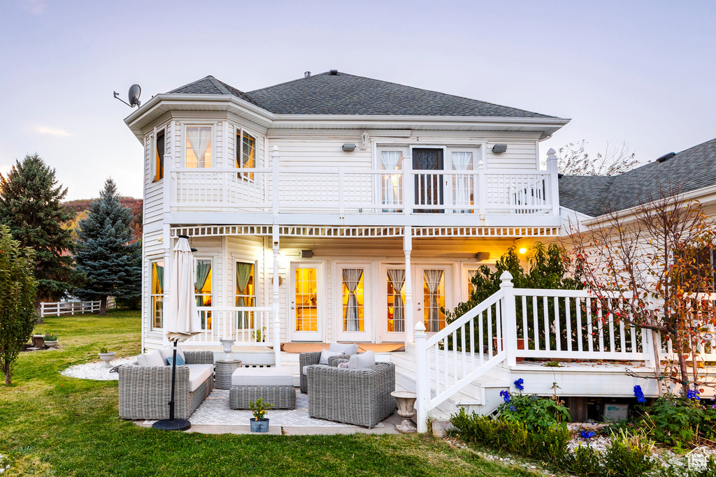 Rear view of house with an outdoor hangout area, a yard, roof with shingles, and a balcony