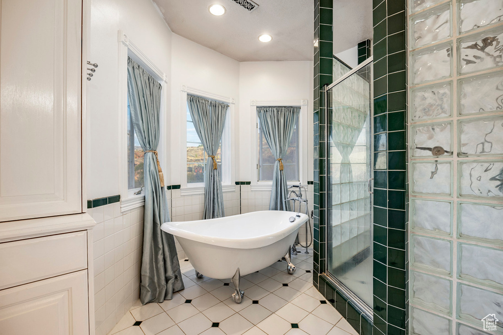 Bathroom with tile patterned floors, tiled shower, recessed lighting, tile walls, and a soaking tub