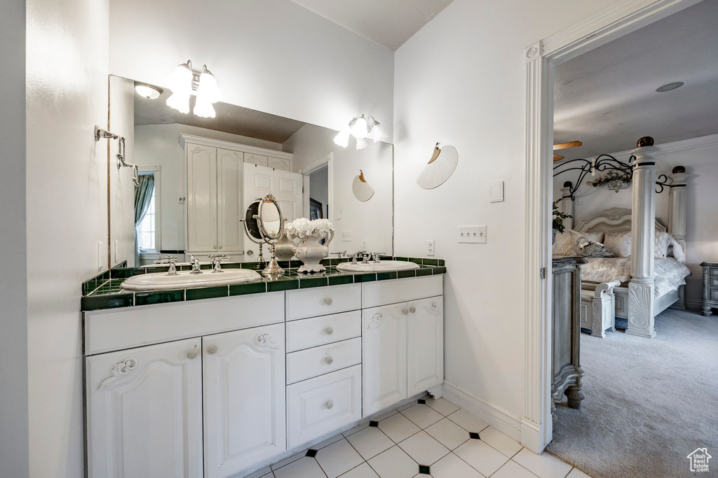 Full bath with double vanity, baseboards, tile patterned flooring, and a sink