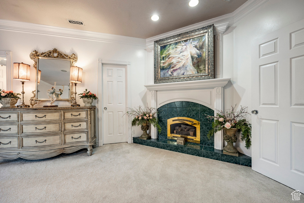 Living area featuring crown molding, carpet flooring, visible vents, and a tile fireplace