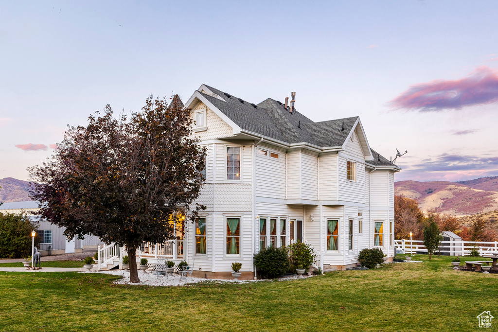 Property exterior at dusk featuring a yard, fence, and a mountain view