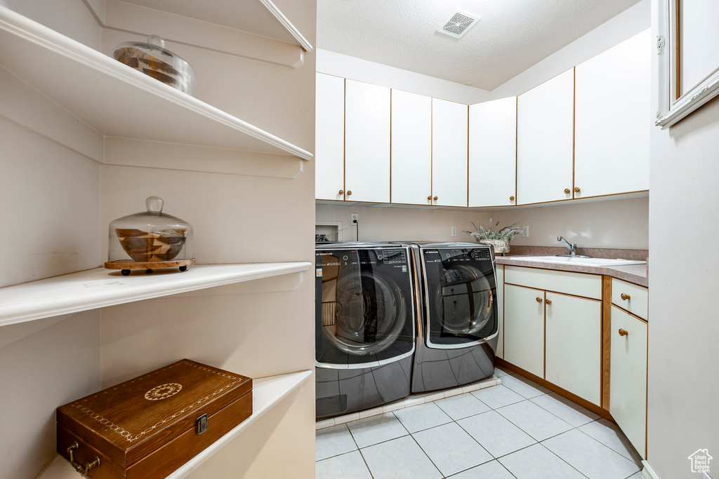 Laundry area with independent washer and dryer, visible vents, cabinet space, a sink, and light tile patterned floors