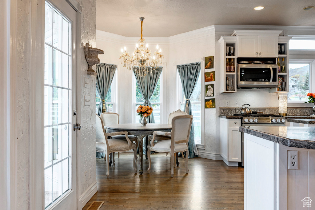 Dining room featuring baseboards, visible vents, dark wood-style flooring, and a notable chandelier