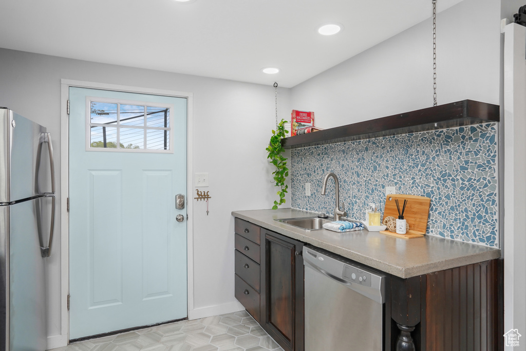 Kitchen featuring appliances with stainless steel finishes, dark brown cabinets, decorative backsplash, and sink