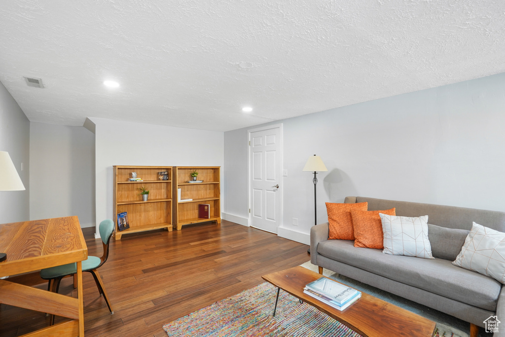 Living room featuring a textured ceiling and dark hardwood / wood-style floors