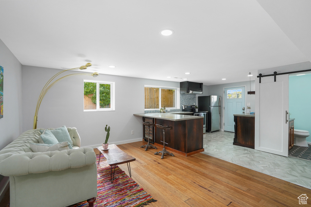 Living room featuring a barn door, light wood-type flooring, and ceiling fan