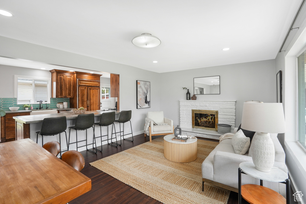 Living room with a healthy amount of sunlight, sink, a stone fireplace, and dark hardwood / wood-style floors