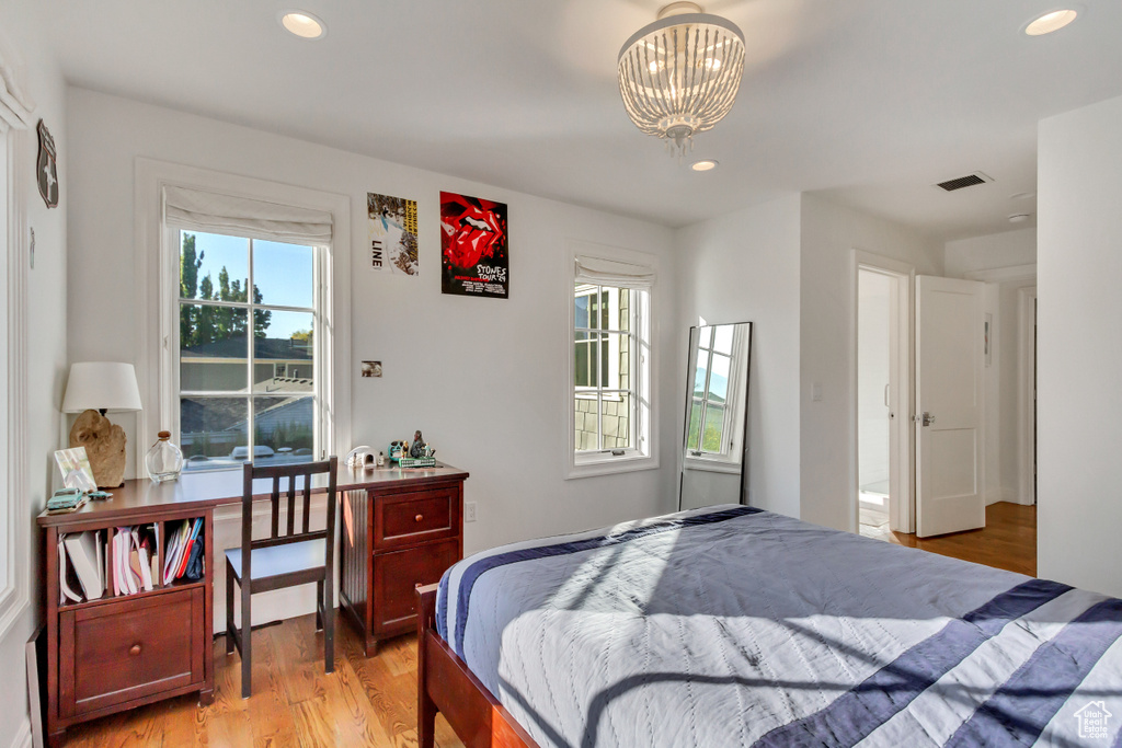 Bedroom featuring a chandelier, light hardwood / wood-style floors, and multiple windows