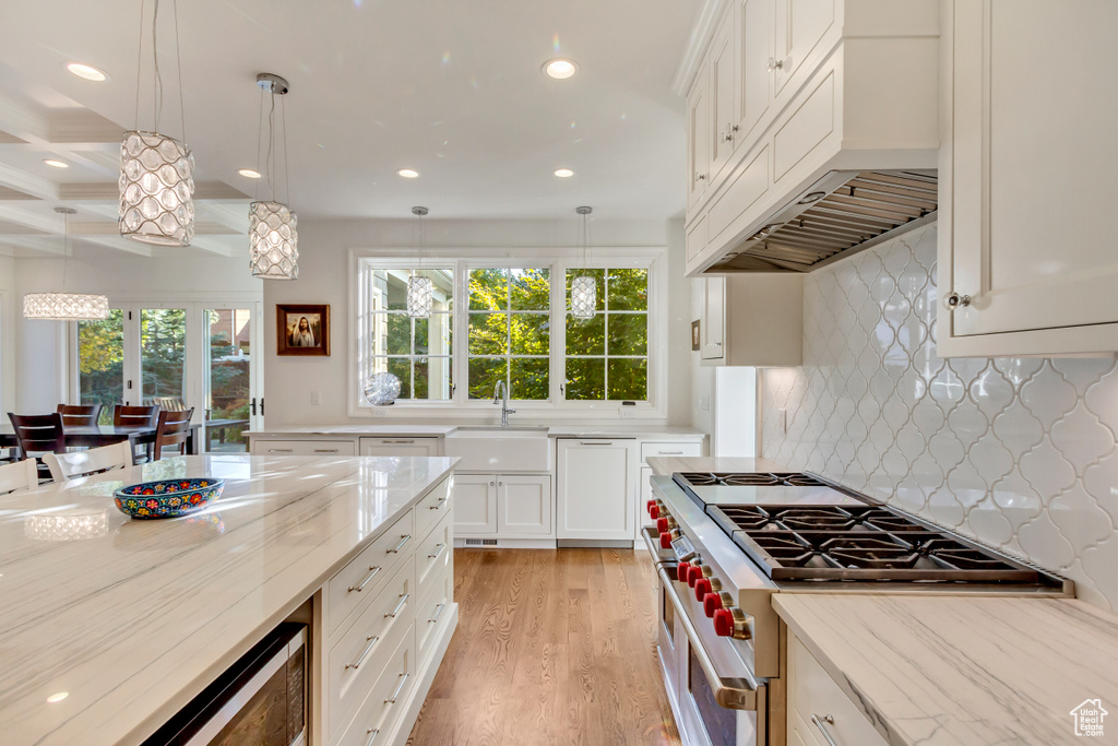 Kitchen featuring decorative light fixtures, high end stove, sink, and light hardwood / wood-style flooring