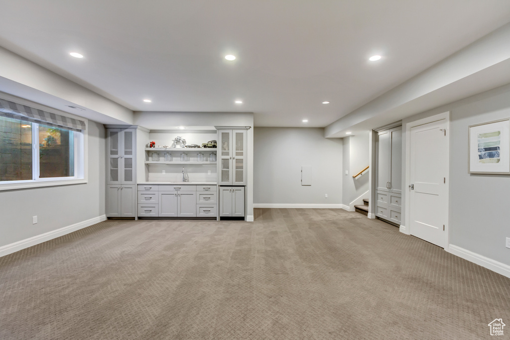 Unfurnished living room with light colored carpet and sink