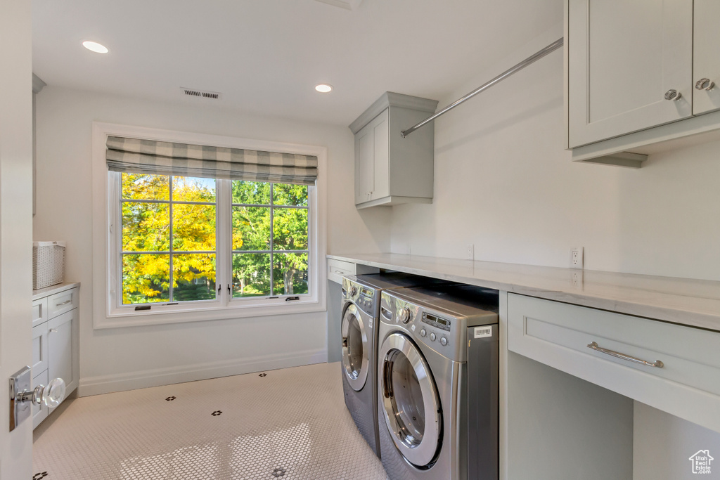 Laundry area featuring washing machine and clothes dryer and cabinets