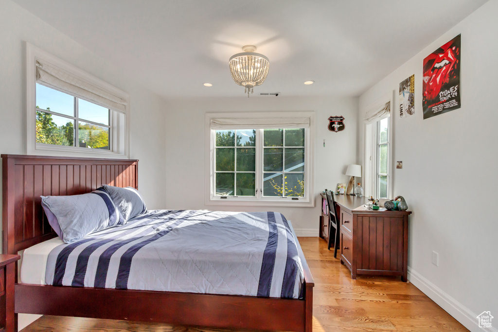 Bedroom featuring multiple windows, an inviting chandelier, and light wood-type flooring