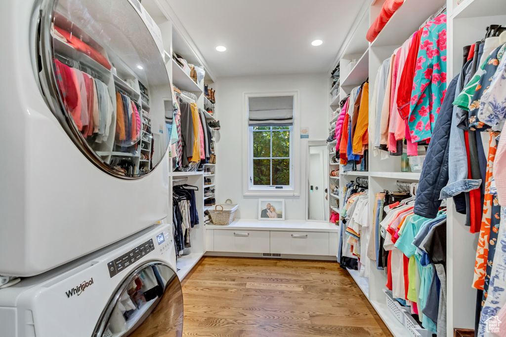 Spacious closet featuring light hardwood / wood-style flooring and stacked washer / dryer