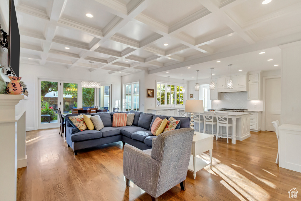 Living room with coffered ceiling, beamed ceiling, light hardwood / wood-style flooring, and crown molding