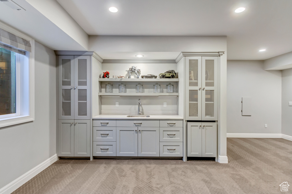 Bar featuring gray cabinets, sink, and light carpet