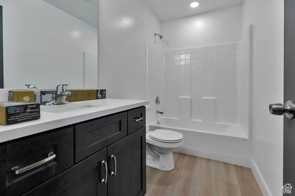 Full bathroom with wood-type flooring, tub / shower combination, vanity, and toilet