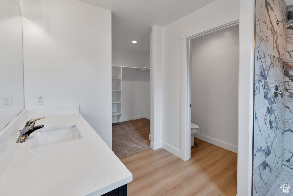 Bathroom featuring wood-type flooring, vanity, walk in shower, and toilet