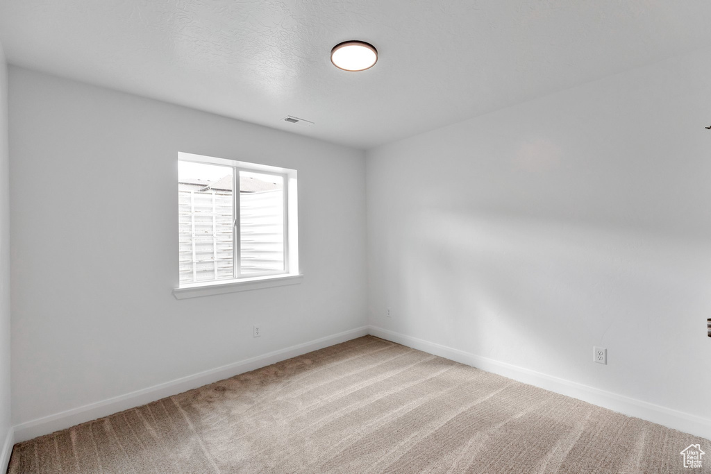 Unfurnished room featuring a textured ceiling and carpet